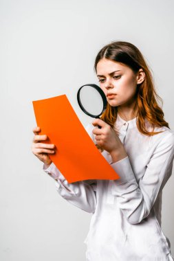 Büyüteç aracılığıyla belgeleri dalgın genç kız Beyaz gömlekli bakar