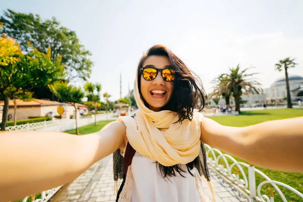 A bright happy girl in a scarf makes a selfie, a photo of herself. Exchange student on vacation — Stock Photo, Image