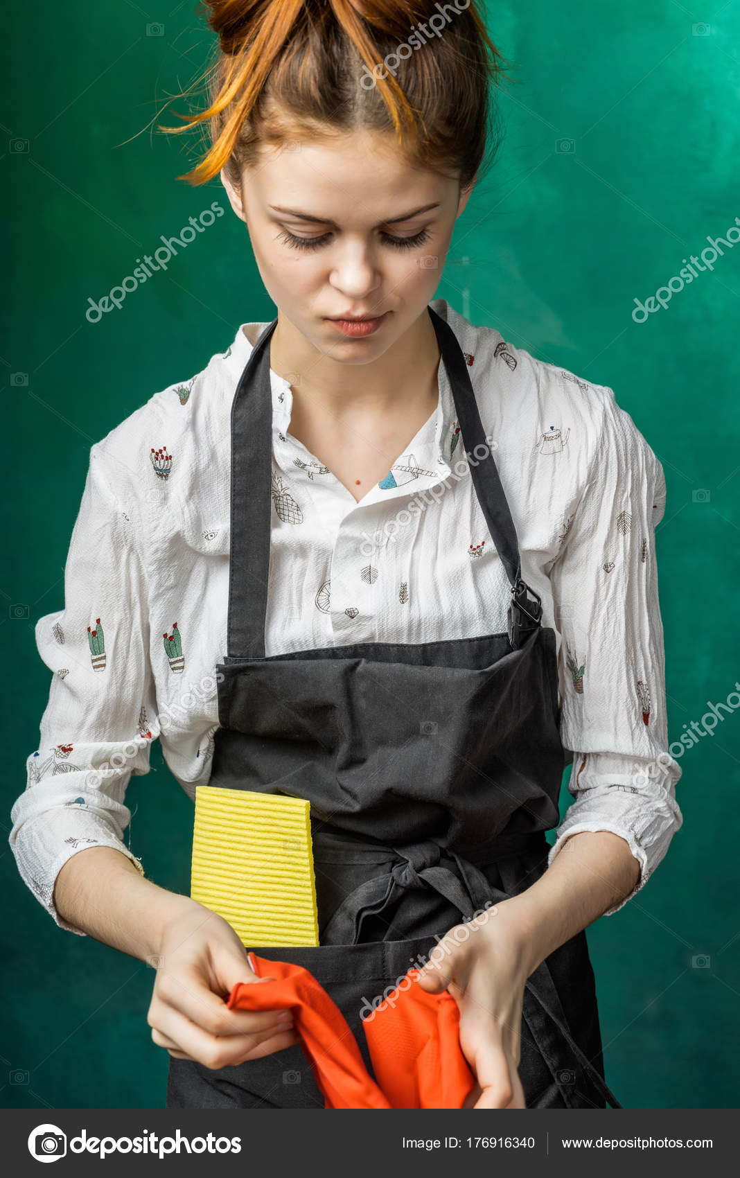 A young girl in a black apron puts on orange rubber gloves for cleaning — Stock Photo © mne_len