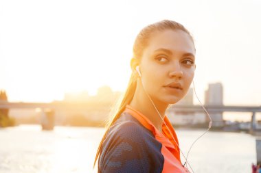 genç güzel dalgın kız güneş ve nehir arka planı Kulaklığımda müzik dinler