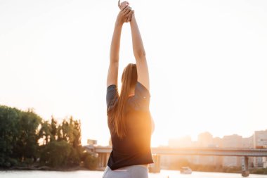 gün batımı ve nehir fonunda koşu önce kaslar yoğurma uzun saçlı atletik kız