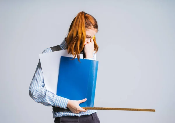 Müde müde traurige rothaarige Schülerin hält Bildungsdokumente und ein Lineal in den Händen — Stockfoto