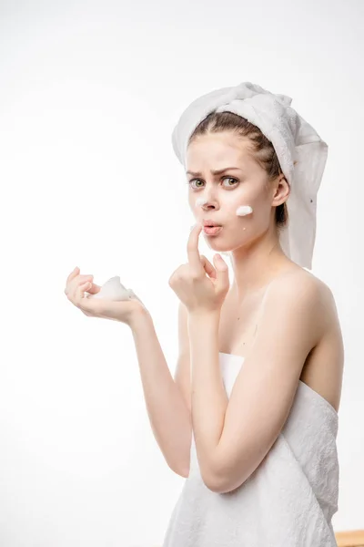 Удивленный молодой девушки с белым полотенцем на голове очищает лицо с пеной — стоковое фото