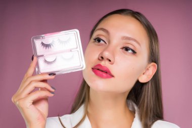 çekici güzel kız ile sahte kirpik ambalaj elinde tutan