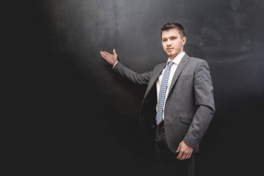 bir şey üzerinde gösterilen emin başarılı adam siyah arka plan üzerine poz takım elbiseli