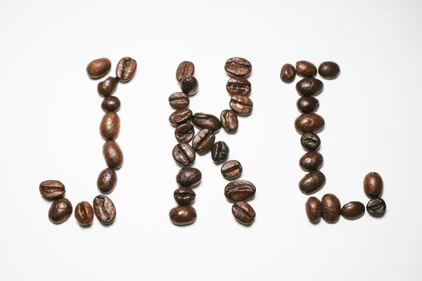 Auf weißem Hintergrund liegen die Körner des brasilianischen Kaffees in Form von Buchstaben j k l — Stockfoto