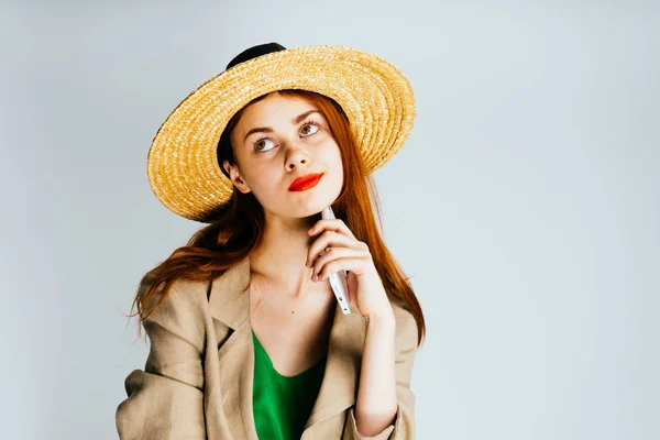 Мечтательная задумчивая девушка в соломенной шляпе и зеленой куртке смотрит вверх — стоковое фото