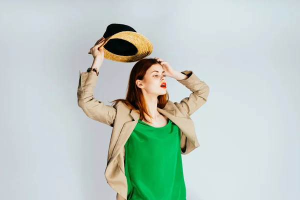 Ελκυστική κοπέλα σε ένα πράσινο πουλόβερ βάζει ένα ψάθινο καπέλο στα χέρια — Φωτογραφία Αρχείου