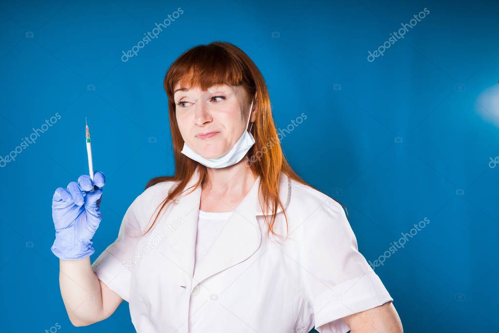smiling adult woman doctor in white medical dressing gown holds syringe for injection