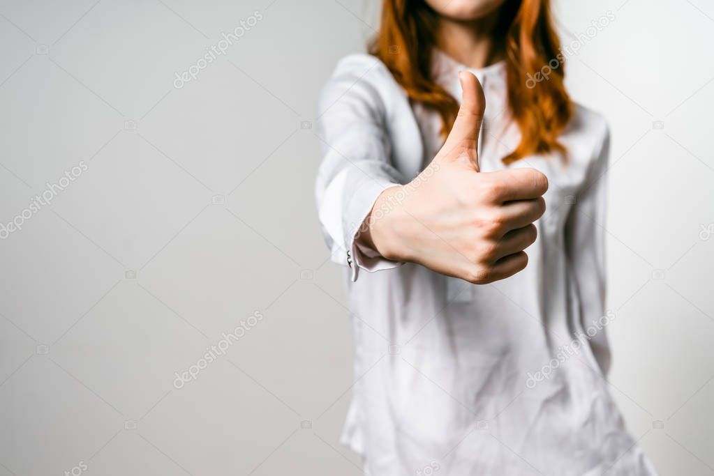 red-haired woman in white shirt shows thumb up