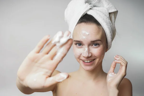 Funny woman in a towel on the head happy cleanses the skin with foam on a white background isolated. Skincare cleansing concept — Stock Photo, Image