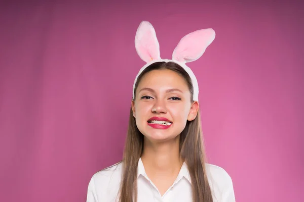 Una giovane ragazza divertente con una camicia bianca, sulla testa un orlo sotto forma di orecchie di coniglio, gomma da masticare — Foto Stock
