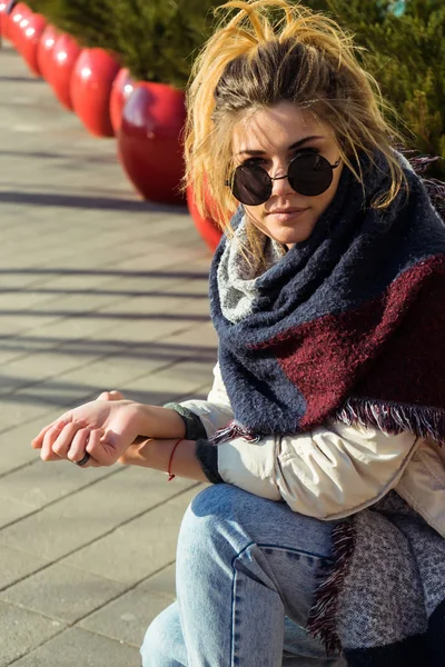Стильная городская девушка в модных солнечных очках сидит на улице под солнцем — стоковое фото