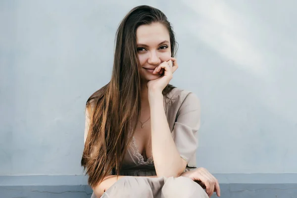 Atractiva brillante joven modelo posando sobre fondo blanco de la pared, sonriendo, recostando su cabeza en el brazo — Foto de Stock