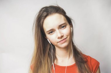 beyaz kulaklık müzik dinlemek ve gülümseyen uzun saçlı genç kız