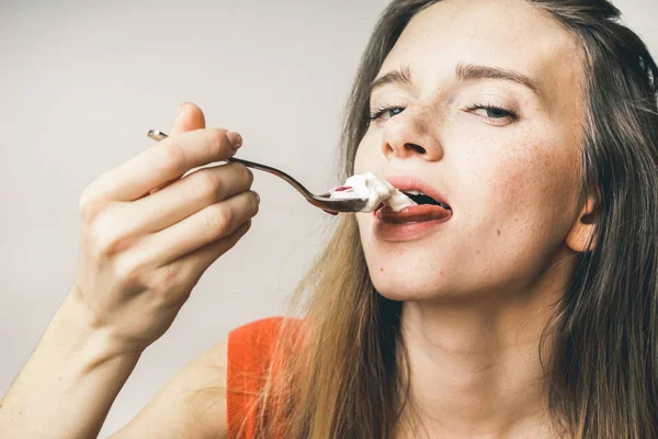 Женщина наслаждается вкусной едой, полный рот, в оранжевой футболке — стоковое фото