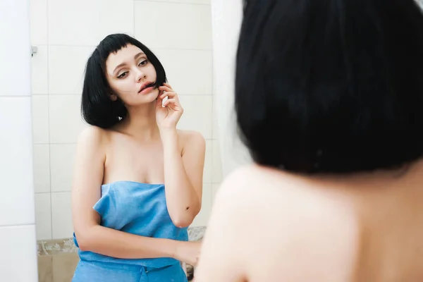 Приваблива сексуальна дівчина з чорним волоссям дивиться на себе у дзеркало — стокове фото
