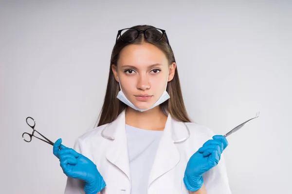 Bella giovane ragazza medico in guanti blu tiene strumenti dentali in mano — Foto Stock