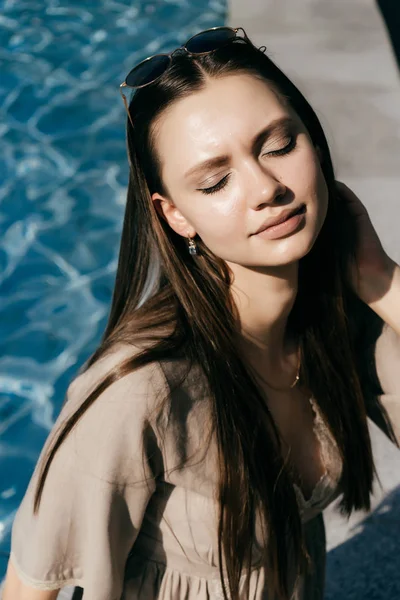 Attraente bella ragazza modello in posa al sole, sullo sfondo di acqua, gli occhi chiusi — Foto Stock