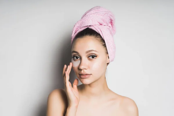 Молодая красивая девушка заботится о себе, на голове полотенце, под глазами силиконовых пятен — стоковое фото