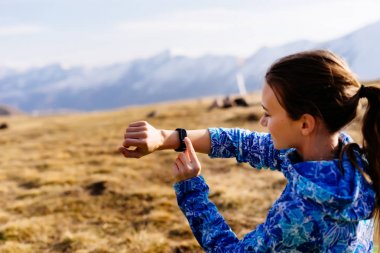a young active girl travels through the Caucasus mountains, watches time on a wristwatch