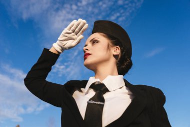 mavi gökyüzüne karşı mesafe içine kendine güvenen genç kız hostes görünüyor