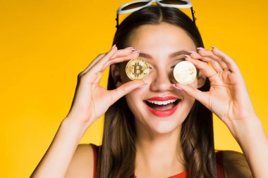 Kırmızı ruj ile mutlu gülümseyen kız altın bitcoins onun elinde tutan, gözlerini kapatır