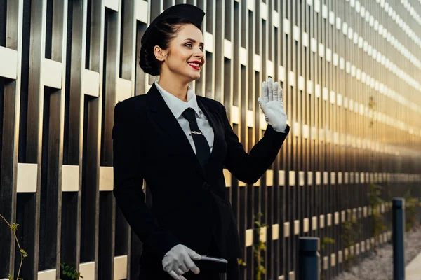 Letuška krásná mladá žena v uniformě s úsměvem, čekání na letadlo — Stock fotografie