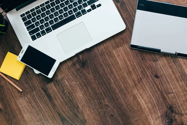 Op een houten oppervlak is een laptop, een grafisch tablet en een smartphone voor werk — Stockfoto