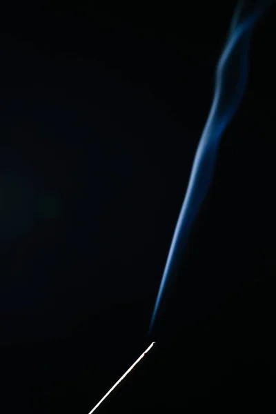A sötét háttéren parázsló illatos-stick kék füst — Stock Fotó