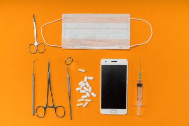 Turuncu yüzeyinde diş aletleri, Tablet ve bir akıllı telefon vardır