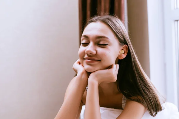 Feliz sorrindo menina recentemente acordou, senta-se na cama e não quer se levantar — Fotografia de Stock