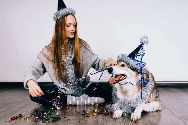 Rousse fille élégante se prépare pour la nouvelle année, tinsel brillant, assis sur le sol avec son gros chien — Photo