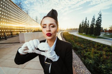 güzel kız hostes üniforması ve beyaz eldiven bir hava öpücük gönderir