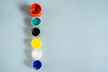 mavi bir masanın üzerine guaş ile çok renkli kavanozlar vardır