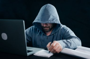 gizemli bir suç adam yüzünü bir hacker gizler, bir şey yazıyor