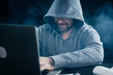 Yüzünü bir dizüstü gülümseyen yasadışı bir şey yapıyor başlıklı gizemli gizemli adam hacker gizler