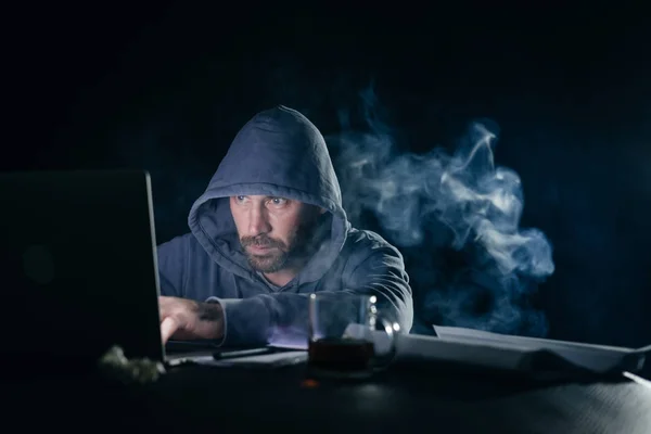 Mysterieuze geheimzinnige man hacker in kap verbergt zijn gezicht iets illegaal op laptop — Stockfoto