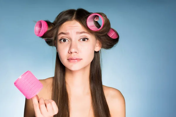 Грустная девушка не может сделать прическу на голове большие розовые волосы бигуди — стоковое фото