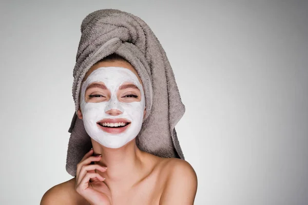 Una chica riendo con una toalla en la cabeza, dientes blancos, una mascarilla —  Fotos de Stock