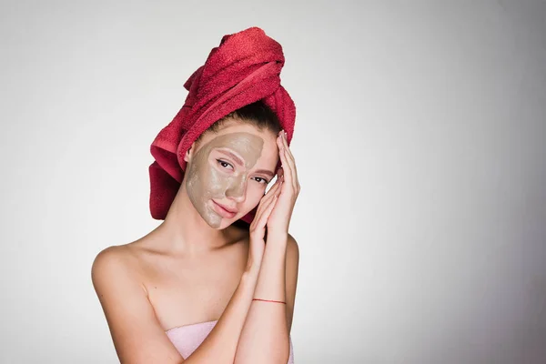 Ung flicka poserar, på halva ansiktet bra lermask, på huvudet handduk — Stockfoto