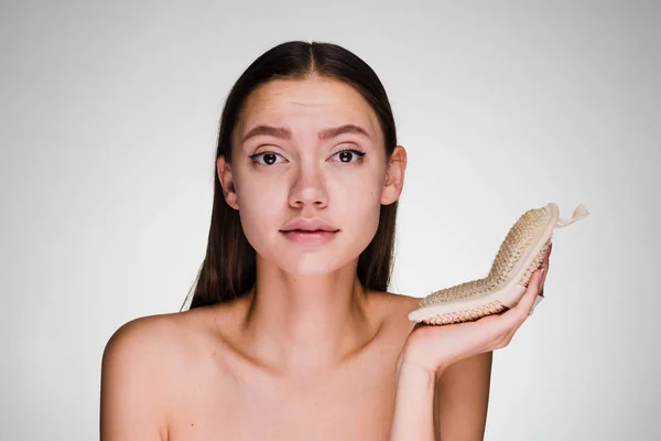 Ein junges Mädchen blickt in die Kamera, hält ein Reinigungsmittel für das Gesicht in der Hand — Stockfoto