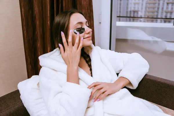 Menina sorridente feliz em um casaco branco acabou de acordar, sob os olhos manchas pretas contra o inchaço — Fotografia de Stock