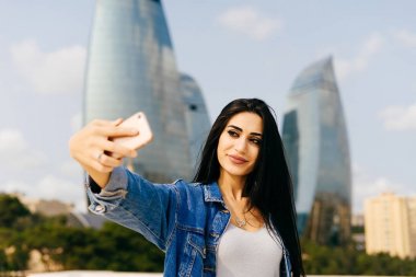 Azerbaycan Bakü şehrin modern mimari arka plan üzerinde selfie çekici siyah saçlı kız yapar