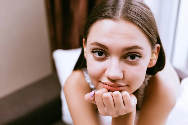Młoda piękna dziewczyna siedzi na łóżku i patrzy w kamerę — Zdjęcie stockowe