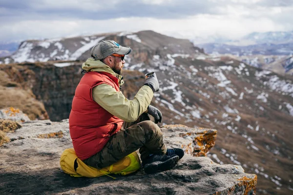 Mužské cestující sedí na okraji útesu. Příroda a čistý horský vzduch, horký čaj nápoje — Stock fotografie