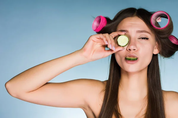 Mladá dívka chce vypadat dobře, na hlavě kulma, okurka hydratují pokožku na tváři je držitelem — Stock fotografie