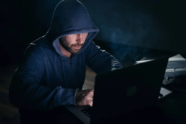 신비한 위험한 젊은이 그의 얼굴을 숨기고, 노트북에 불법적인 뭔가 하 고, 해킹 — 스톡 사진