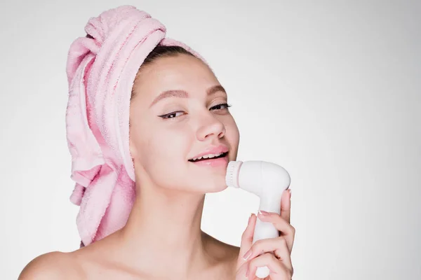 Sorrindo menina atraente fazendo limpeza profunda da pele no rosto usando escova elétrica especial — Fotografia de Stock