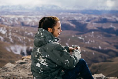 Genç bir kız bir dağ üzerinde oturur, doğa ve temiz hava sahiptir